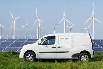 Electric van in front of solar panels and wind turbines by . 
