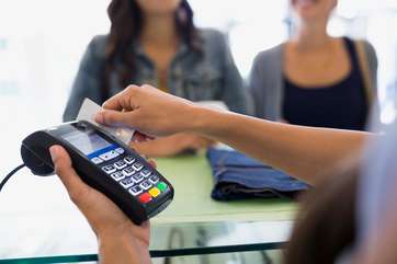 Worker swiping credit card reader in shop by .