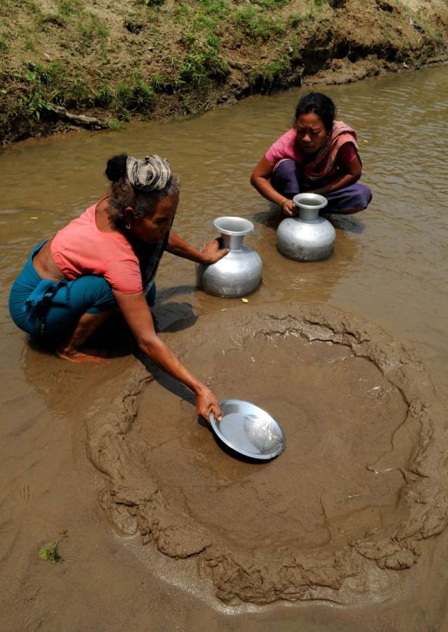 Agartala: Tribal women collect water from a dry spring after filtering it using their indigenous process in Karbonpara, near Agartala on April 28, 2016. (Photo: IANS) by . 