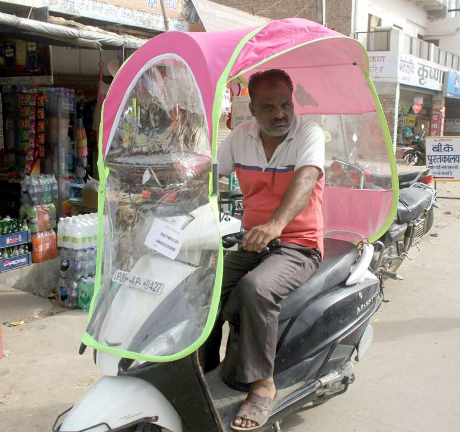 Mathura: A man riding a two-wheeler fitted with an umbrella to beat the scorching heat in Mathura on April 22, 2017. (Photo: IANS) by . 