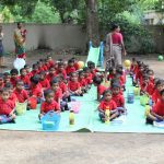 Students dressed in their red school uniforms assemble in the lawn for nutritious meals provided by the school. by .