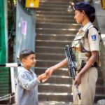Woman CRPF personal shaking hands with kid in Kashmir. by . 