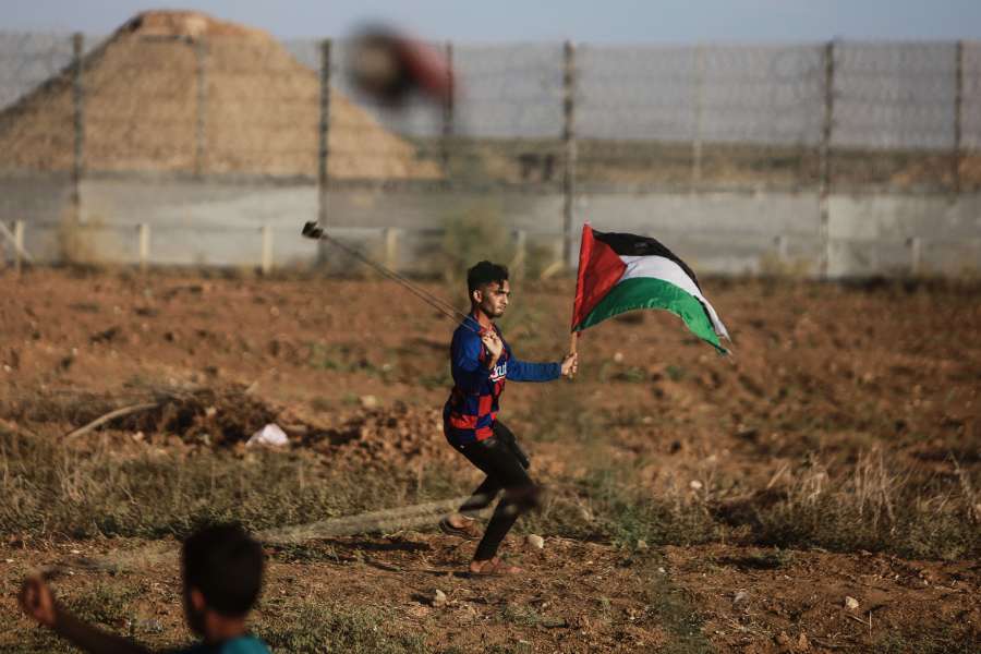 GAZA, Oct. 11, 2019 (Xinhua) -- A Palestinian protester uses a slingshot to throw a stone at Israeli troops during clashes on the Gaza-Israel border, east of Gaza City, on Oct. 11, 2019. At least 49 Palestinians were injured on Friday afternoon during clashes between hundreds of Palestinian demonstrators and Israeli soldiers in the eastern Gaza Strip close to the border with Israel, a local official said. (Photo by Mohammed Dahman/Xinhua/IANS) by . 
