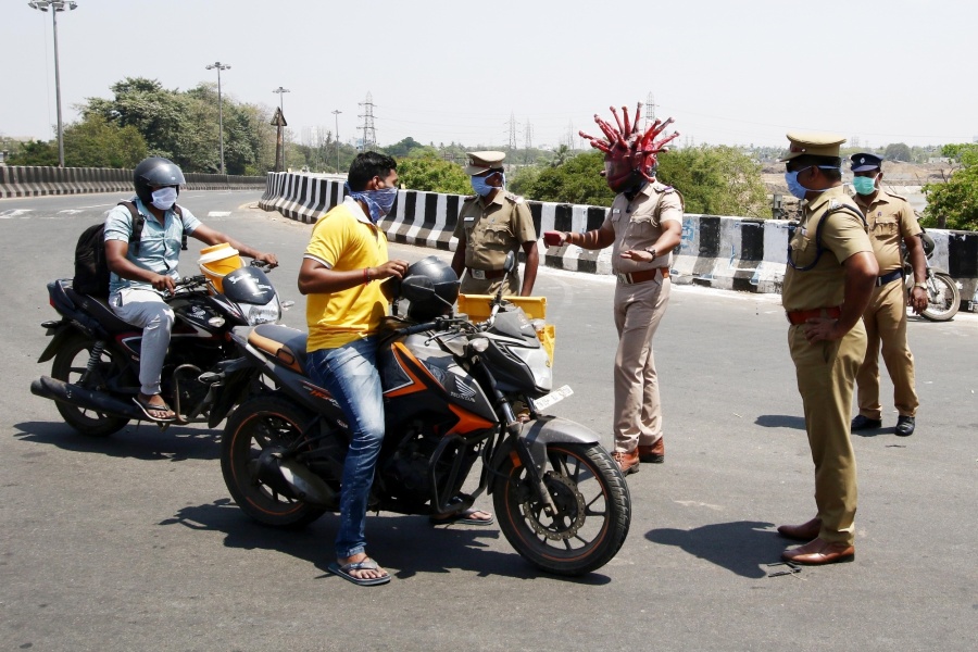 Chennai: A Chennai cop wearing a 'Corona Helmet' intercepts a lockdown violater on March 29, 2020. The cop wearing the helmet, police Inspector Rajesh Babu in collaboration with a local artist Gowtham had come with this innovative initiative to dissuade people from flouting the curfew and make them undertand the severity of the disease. The helmet that has a scary and eerie appearance, has been designed loosely based on a close up of what a singular representation of the virus looks like. Coronavirus (COVID-19) has a crown-like appearance and the spikes on its surface gives this virus its family name, corona which means crown in Latin. As per the latest statistcs from the World Health Organsation, there are 575,444 cofirmed cases of Coronavirus across 202 nations with 26,654 deaths. Cases across India surged to 974 with 109 new cases on Saturday. The death toll in the country touched 27 with Delhi, Kerela, Telangana, Gujarat and Maharashtra confirming one death each. In order to contain the spead of COVID-19, Prime Minister Narendra Modi had announced a 21 day nationwide lockdown imposed in 560 districts in 32 states and union territories across the country that came into effect on the intervening night of March 24 and 25 and shall continue till April 14. (Photo: IANS) by .