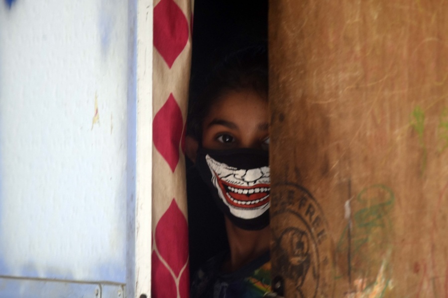 Mumbai: A girl seen wearing a homemade mask peeps out from the gate of her house in Mumbai during the extended nationwide lockdown imposed to mitigate the spread of coronavirus, on May 4, 2020. (Photo: IANS) by . 