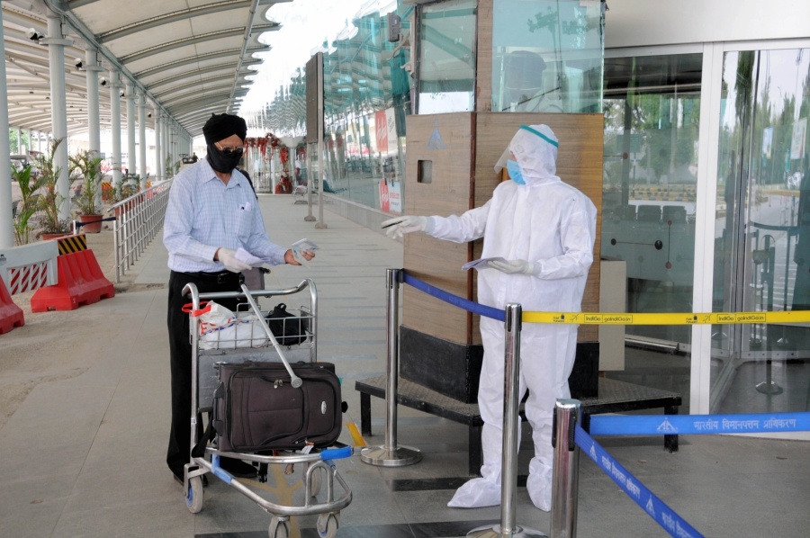 Amritsar: A security personnel wearing Personel Protective Equipment (PPE) suit checks the passports of British nationals before check-in for a special flight to London during the extended nationwide lockdown imposed to mitigate the spread of coronavirus; at the Sri Guru Ram Dass Jee International Airport in Amritsar on Apr 25, 2020. (Photo: IANS) by . 