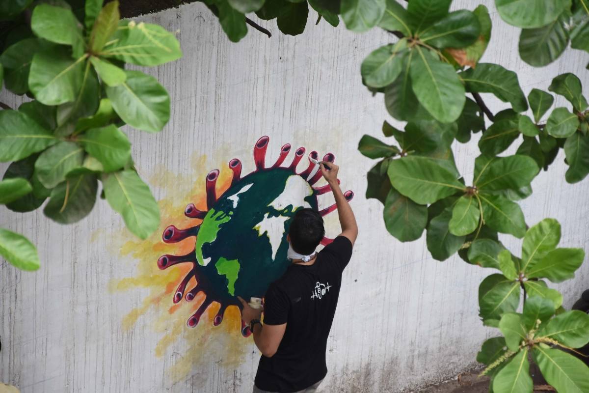 Mumbai: An artist paints a wall graffiti of the 'Earth trapped in COVID-19 pandemic' in Mumbai on June 2, 2020. (Photo: IANS) by . 