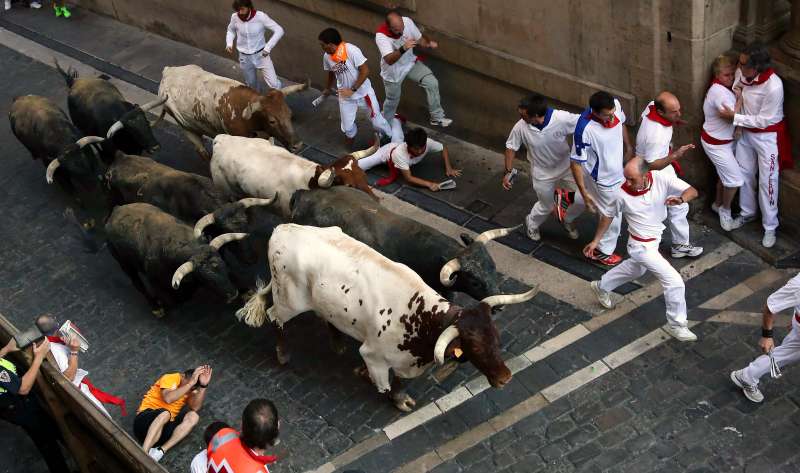 Several runners or 'mozos' are chased by bulls from Miura ranch during the last bullrun of Sanfermines 2015 in Pamplona, northern Spain. The festivities will end with thousands people signing the traditional 'pobre de mi' (poor me) in City Hall square this night.