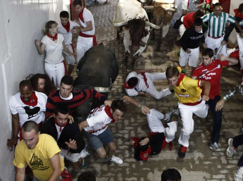 Several runners or 'mozos' are chased by bulls from Miura ranch during the last bullrun of Sanfermines 2015 in Pamplona, northern Spain. The festivities will end with thousands people signing the traditional 'pobre de mi' (poor me) in City Hall square this night.