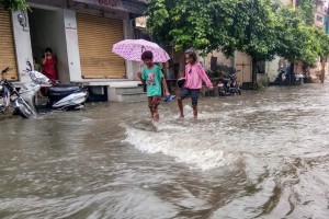 Bhilwara: Children struggle through a water-logged street after heavy rains, in Rajasthan's Bhilwara on Aug 16, 2019. (Photo: Shaukat Ahmed/IANS)